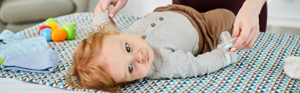 A baby lays on a bed, joyfully playing with his mom in a cozy home setting.