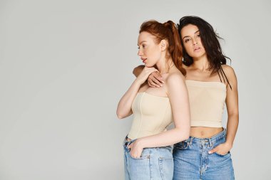 İki genç kadın, sevecen lezbiyen bir çift, yan yana dururlar zarif giysiler içinde, mutluluk saçarak.