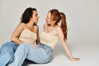 Şık giyinmiş, yere yakın oturan zarif aşık kadınlar..