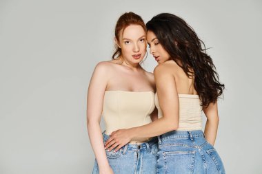 Zarif giyinmiş iki genç kadın birbirlerine sevgiyle sarılıyorlar..