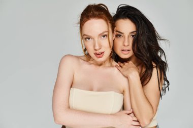 İki kadın, birbirini seven lezbiyen bir çift, zarif giysiler içinde birbirlerini kucaklarlar..