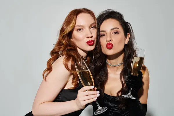 stock image A loving lesbian couple in elegant attire, happily holding wine glasses.