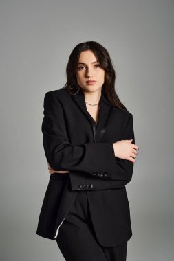 Stylish plus size woman rocks a black suit, exuding confidence and grace on a neutral backdrop. clipart