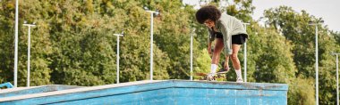 A youthful woman with a skateboard glides gracefully along the edge of a pool, showcasing his skills to those around him. clipart