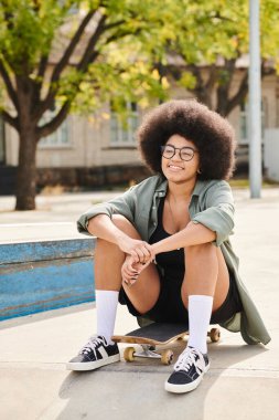 A stylish young African American woman with a voluminous afro hairdo leisurely sits on a skateboard at a vibrant skate park. clipart