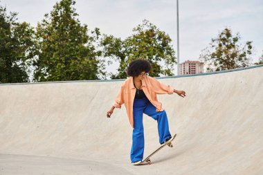 A young African American woman with curly hair boldly rides her skateboard up the side of a ramp at the skate park. clipart