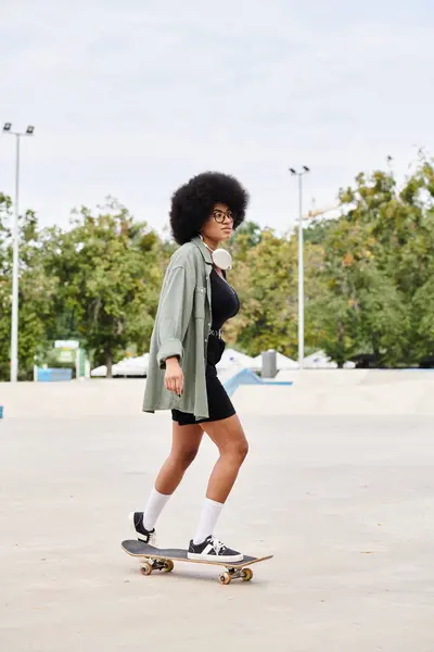 stock image A young African American woman with curly hair effortlessly rides a skateboard in a busy parking lot.