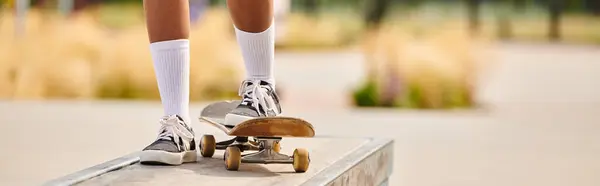 stock image A young African American woman confidently rides a skateboard on a ramp at a skate park.