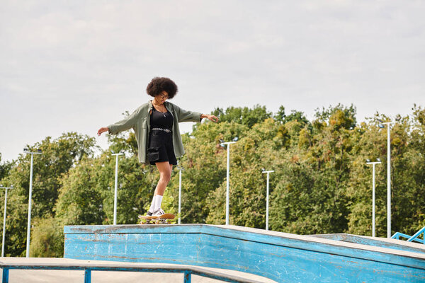 A young African American woman with curly hair skillfully skateboarding on the edge of a pool in an outdoor skate park.