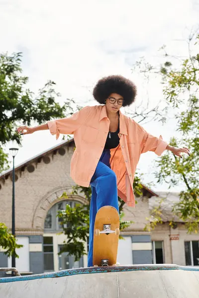 カーリーヘアの若いアフリカ系アメリカ人女性は アウトドアスケートパークのランプの側面にスケートボードに乗ります — ストック写真