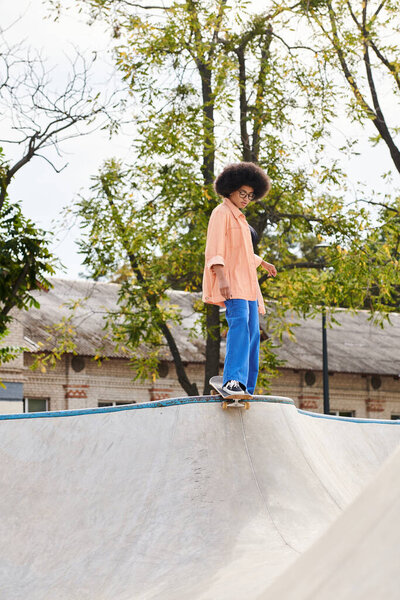 A young man with curly hair is skillfully riding a skateboard on top of a ramp in a skate park, showcasing his impressive tricks and maneuvers.
