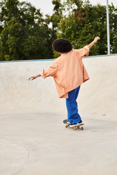 A young African American boy with curly hair confidently rides his skateboard at a bustling skate park.