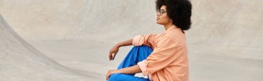 A young African American woman with curly hair confidently sits on a skateboard at a bustling urban skate park. clipart