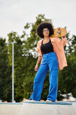 Afro saçlı genç bir Afrikalı Amerikalı kadın kaykay parkında zarif bir şekilde kaykay tutarken yeteneklerini sergiliyor..