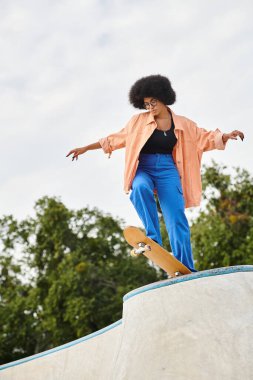 Kıvırcık saçlı Afro-Amerikalı bir kadın kaykay parkında kaykaya biniyor..