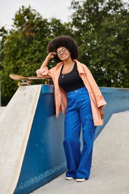 A young African American woman with curly hair skillfully skateboarding next to a ramp in an outdoor skate park. clipart