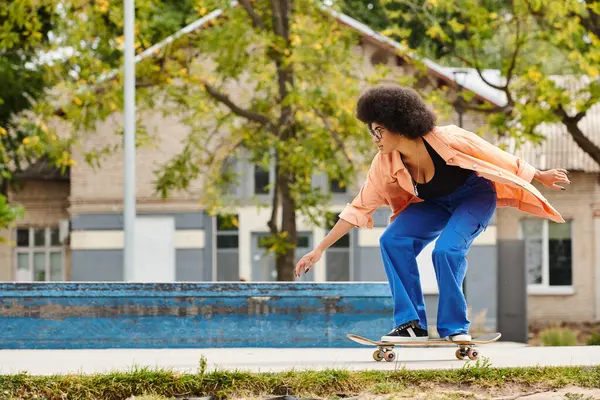 スケートボードを持つ若いアフリカ系アメリカ人女性は 都市スケートパークのスイミングプールの隣にスケートボードをしています — ストック写真