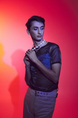 Çekici, zarif, rahat giyimli, neşeli arka planda poz veren ve başka yöne bakan bir gay.