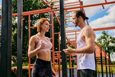 Spor giyim sektöründe bir erkek ve kadın yan yana durur, dışarıda egzersiz yaparken azim ve motivasyon yayarlar..