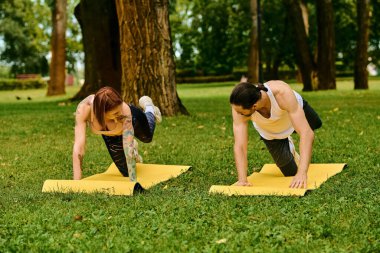 Spor giyim sektöründe bir erkek ve kadın, açık hava seansı sırasında azim ve motivasyonla yoga pozisyonuna girerler..
