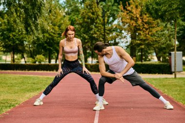 A determined man and woman, dressed in sportswear, engaging in a stretching exercise clipart