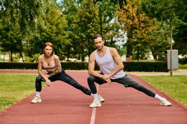 Spor giyim sektöründe bir kadın antrenörün rehberliğinde esneme egzersizi yapıyor, azim ve motivasyon sergiliyor..
