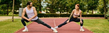 Spor giyimli bir kadın, spor eğitmeninin rehberliğinde, dışarıda sakin bir park ortamında çalışırken azim ve motivasyon gösteriyor..