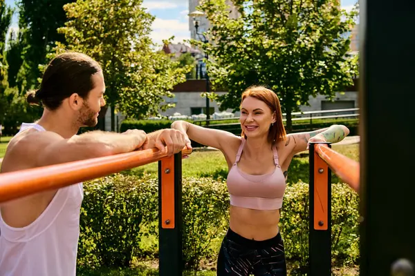 A determined man and woman, in sportswear, work out together outdoors, displaying motivation and focus.