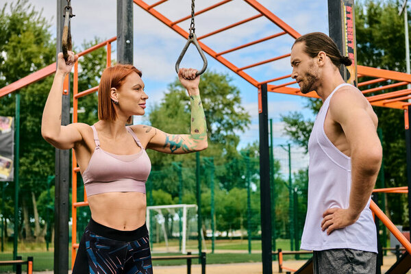 A determined woman, guided by a personal trainer, exercise outdoors in sportswear.