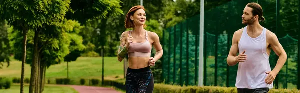 スポーツウェアの男女が公園で一緒にジョギングし 個人のトレーナーによって導かれ 決意と動機によって駆動 — ストック写真