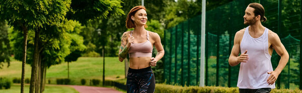 A man and woman clad in sportswear jog together in the park, guided by a personal trainer, driven by determination and motivation.