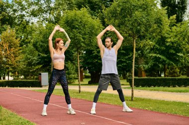 A personal trainer guides a woman in sportswear in a vibrant park setting, showcasing determination and motivation. clipart