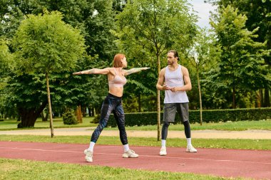 Spor kıyafetleri içinde bir erkek ve bir kadın dışarıda gerinip motivasyon gösteriyorlar..