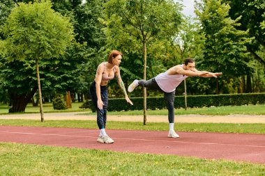 Çimlerde spor kıyafetleri giyen bir kadın, kişisel antrenörleri tarafından yönlendiriliyor. Kararlılıkları ve motivasyonları.