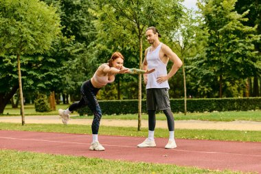 Bir erkek ve kadın spor giyim, çimenler üzerinde egzersiz yapıyor, azim ve motivasyon gösteriyor..