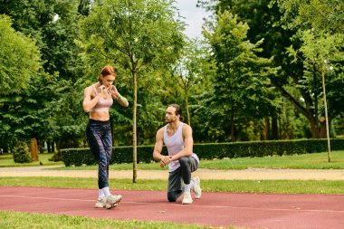 Kişisel antrenör, spor kıyafetleri içinde bir kadına parktaki bir bankta egzersiz yaptırarak azim ve motivasyon göstererek yol gösterir..