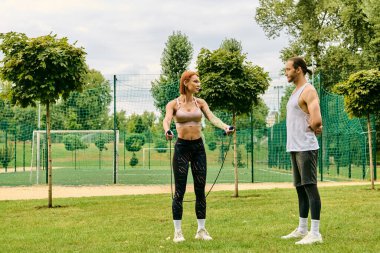 Spor giyim sektöründe kararlı bir kadın çimenlerde egzersiz yaparken kişisel antrenörün rehberliğinde..