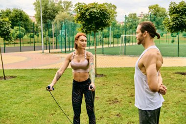 Spor giyimli bir kadın parkta kişisel antrenörüyle antrenman yapıyor, azim ve motivasyon gösteriyor..