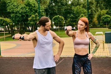 Spor giyimli kararlı bir kadın, özel antrenörüyle tenis kortunda egzersiz yapıyor..