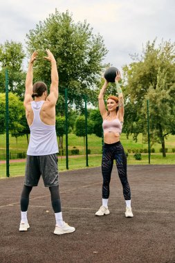 A personal trainer motivates a woman in sportswear as they workout together outdoors with determination. clipart