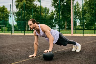 A man in sportswear performing push ups with a ball under the guidance of a personal trainer, showcasing determination and motivation. clipart