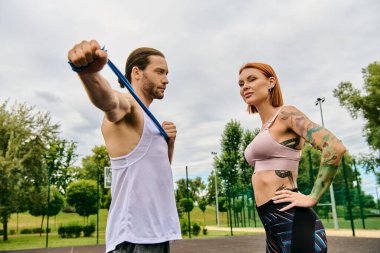 Spor giyimli bir kadın, kişisel antrenörüyle birlikte, azim ve motivasyonla açık hava egzersizlerine girişiyor..