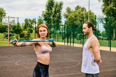 A woman in sportswear stand on a court, displaying determination and motivation while exercising with personal trainer. clipart