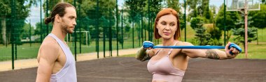 Spor giyim sektöründe bir kadın, kişisel antrenörle antrenman yaparken sahada duruyor..