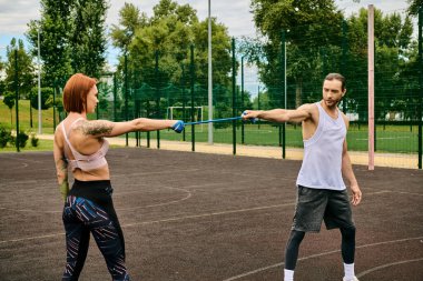 A determined woman in sportswear stands on a court and pulling resistance band with man clipart