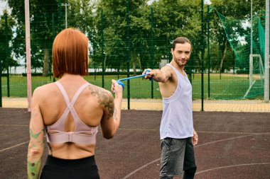 Spor giyimli bir adam kararlı bir kadının yanında direniş bandı tutuyor.