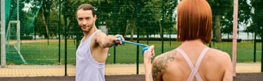 Spor giyimli bir adam kararlı bir kadının önünde direniş bandı tutuyor.