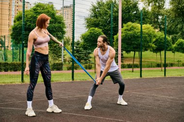 Spor giyim sektöründe kararlı bir erkek ve kadın tenis kortunda durup egzersiz rutinlerine odaklanıyorlar..