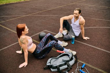 Spor giyim sektöründe kararlı bir kadın yerde kişisel antrenörüyle oturuyor, motivasyon ve kararlılık gösteriyor..
