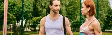 Spor giyim sektöründe bir erkek ve bir kadın açık havada yan yana durur, azim ve motivasyon gösterirler.